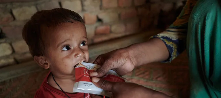 Reshma geeft haar zoon Azaan Ali, 16 maanden oud, therapeutische voedingspasta die ze kreeg in een mobiel gezondheidscentrum ondersteund door UNICEF in Sindh, Pakistan. © UNICEF/UN0705925/Noorani